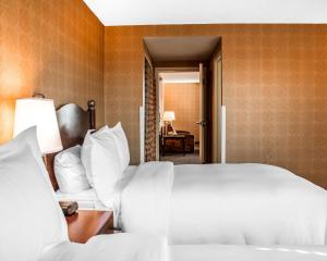 
a hotel room with a white bed and white sheets at The Woodlands Inn, Ascend Hotel Collection in Wilkes-Barre

