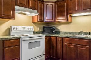 a kitchen with wooden cabinets and a white stove top oven at Comfort Inn Lancaster County in Columbia