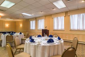 une salle de conférence avec des tables et des chaises et des serviettes bleues dans l'établissement Quality Inn & Suites Conference Center West Chester, à West Chester