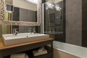 a bathroom with a sink and a mirror and a tub at Logis Hôtel Médiéval, Montélimar Nord in Rochemaure +71 photos