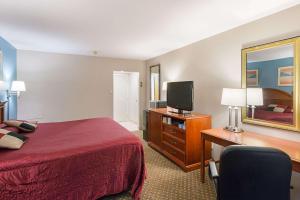 Habitación de hotel con cama, escritorio y TV. en Rodeway Inn Milford - I-84 en Milford