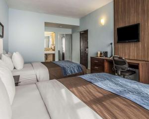 Habitación de hotel con 2 camas y escritorio en Comfort Inn & Suites Levittown, en Levittown