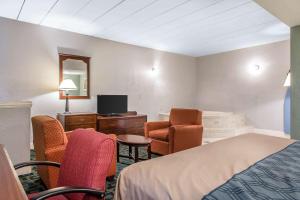 a hotel room with a bed and a desk and chairs at Econo Lodge Cranston - Providence in Cranston