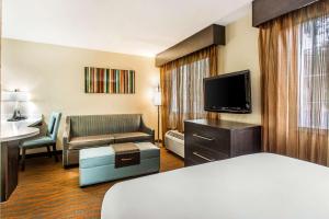 a hotel room with a bed a couch and a television at MainStay Suites Greenville Airport in Greer