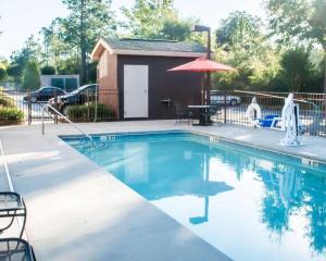 a swimming pool with a house and an umbrella at Sleep Inn in Aiken