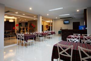Nize Hotel - SHA Plus في فوكيت تاون: مطعم به طاولات وكراسي حمراء وبيضاء