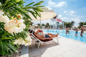 - un couple sur une chaise longue à côté de la piscine dans l'établissement Zaton Holiday Resort, à Nin