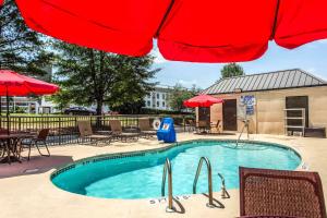 a swimming pool with a red umbrella and tables and chairs at Quality Inn at the Park in Fort Mill +18 photos