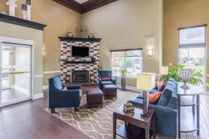 a living room with blue couches and a fireplace at Comfort Inn & Suites Greenwood near University in Greenwood