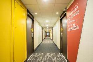 a long hallway with yellow and orange doors and a sign at B&B HOTEL ANNEMASSE Saint-Cergues in Saint-Cergues