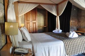 a bedroom with a canopy bed with a phone and a phone at Hotel Rural de Charme Maria da Fonte in Póvoa de Lanhoso