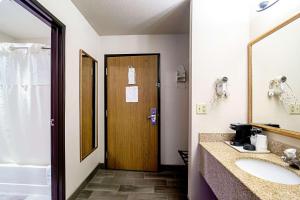 Un baño con lavabo y puerta de madera. en Quality Inn Huron, en Huron
