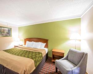 Cette petite chambre comprend un lit et une chaise. dans l'établissement Econo Lodge North, à Knoxville