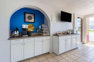 a kitchen with white cabinets and a blue wall at Rodeway Inn Denmark-Jackson in Denmark