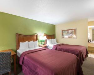 a hotel room with two beds with purple sheets at Quality Inn Merchants Drive in Knoxville