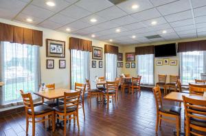 un restaurante con mesas y sillas de madera y ventanas en Quality Inn Hurricane Mills, en Hurricane Mills