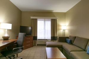 a living room with a couch and a desk and a television at Comfort Suites Austin NW Lakeline in Austin