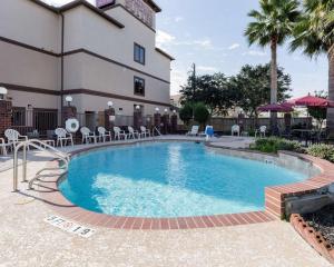 a pool in front of a building with chairs and tables at Comfort Suites Lake Jackson Clute in Lake Jackson