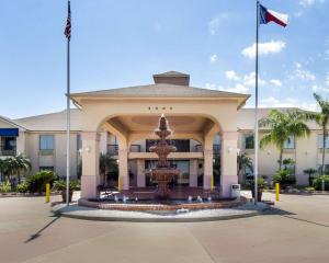 a fountain in front of a building with two flags at Quality Inn Ingleside - Corpus Christi in Ingleside