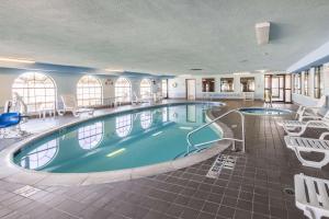 a large pool in a hotel with chairs and tables at Quality Suites, Ft Worth Burleson in Burleson