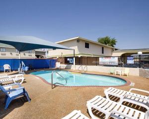 a swimming pool with chairs and a blue umbrella at Rodeway Inn San Antonio Lackland AFB - SeaWorld in San Antonio