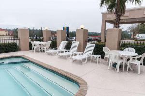 a patio with chairs and a pool and tables and chairs at Comfort Inn North Conroe in Conroe