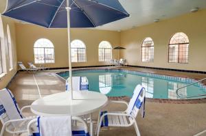 アマリロにあるComfort Inn & Suites Amarillo West near Medical Centerのテーブルとパラソルのあるプール
