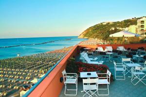 a balcony with tables and chairs and the beach at Giovanna Regina Hotel in Gabicce Mare