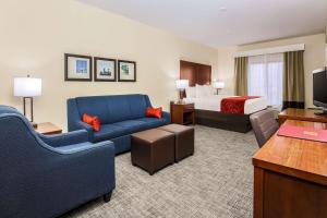 a hotel room with a bed and a blue couch at Comfort Suites DFW N-Grapevine in Grapevine