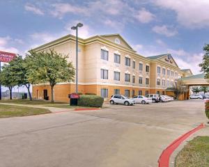 ein großes Gebäude mit Autos auf einem Parkplatz in der Unterkunft Comfort Suites Roanoke - Fort Worth North in Roanoke