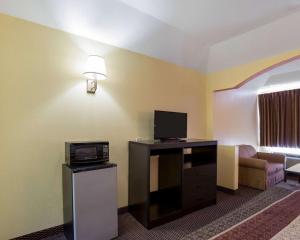 Habitación de hotel con TV y sala de estar. en Rodeway Inn & Suites, en Humble