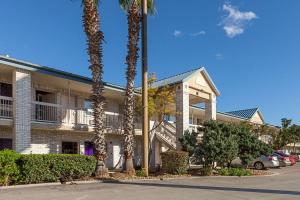 a building with palm trees in front of it at Econo Lodge Downtown South in San Antonio