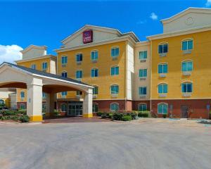 a large yellow hotel with a parking lot at Comfort Suites University in Abilene