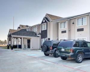 dos autos estacionados en un estacionamiento frente a un edificio en Rodeway Inn & Suites Lewisville I-35 en Lewisville