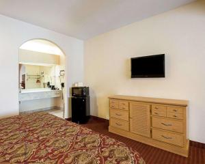 a hotel room with a bed and a flat screen tv at Scottish Inn & Suites IAH West in Westfield