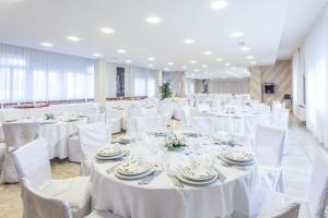 une salle de banquet avec des tables blanches et des chaises blanches dans l'établissement Hotel Ristorante Paladini, à Carisio