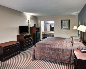 een hotelkamer met een bed en een flatscreen-tv bij Rodeway Inn Gainesville I-35 in Gainesville