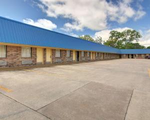 un edificio con techo azul y aparcamiento en Rodeway Inn Gainesville I-35, en Gainesville