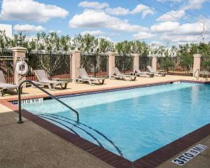 a swimming pool with chaise lounges and chairs around it at Restwell Inn & Suites I-45 North in Houston