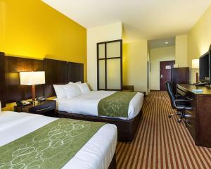 a hotel room with two beds and a desk at Days Inn & Suites by Wyndham Houston / West Energy Corridor in Houston