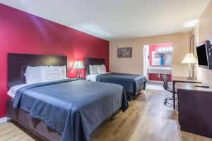 Quality Inn & Suites Bridge City Orange في Bridge City: غرفة فندقية بسريرين وجدار احمر