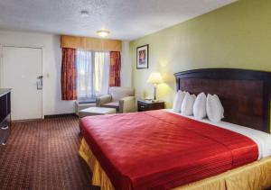 ein Hotelzimmer mit einem großen Bett und einem Stuhl in der Unterkunft Quality Inn in Plainview