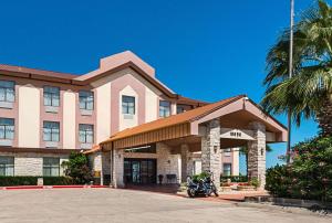 ブダにあるQuality Inn & Suitesのホテルの正面にオートバイが駐車しています