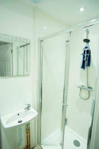 a white bathroom with a shower and a sink at The Ploughman's Rest in Brighton & Hove
