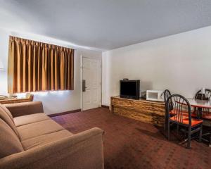 ein Wohnzimmer mit einem Sofa und einem Tisch mit einem TV in der Unterkunft Rodeway Inn Hurricane - Zion National Park Area in Hurricane