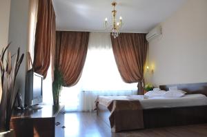 a bedroom with a bed with a television and a window at Ave Hotel Victoriei in Bucharest