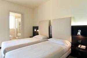 a hotel room with two beds and a bathroom at Hotel Fiera Milano in Rho