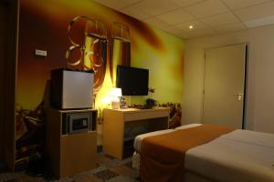 フェンラユにあるDe Witte Hoeveのベッド、デスク、テレビが備わるホテルルームです。