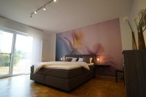 een slaapkamer met een bed met een bloemschilderij aan de muur bij Ferienwohnung am Diersfordter Waldsee in Wesel