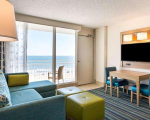 a living room with a couch and a table with a view at Comfort Suites Beachfront in Virginia Beach
